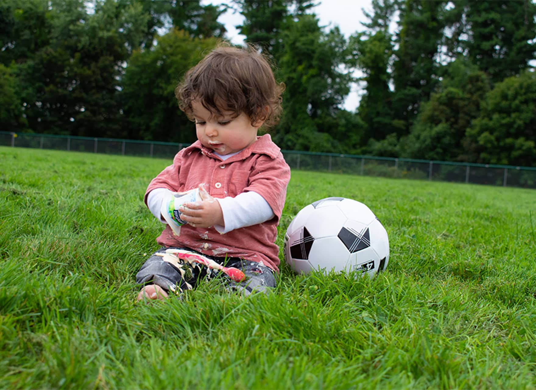 Child sitting on a soccer field eating Stonyfield Organic yogurt